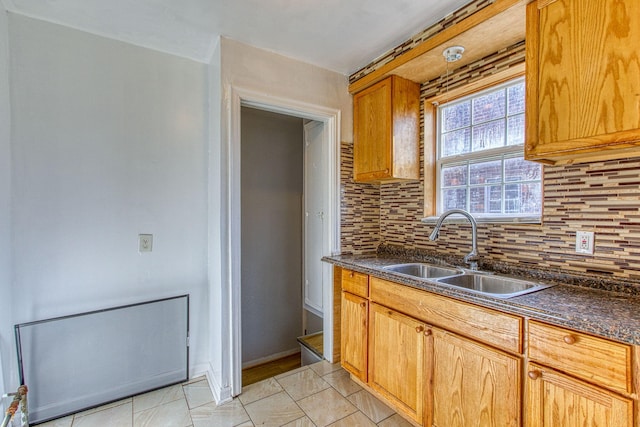 kitchen with tasteful backsplash, sink, light tile patterned floors, and dark stone counters