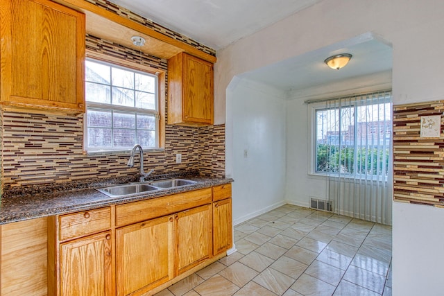 kitchen with plenty of natural light, sink, light tile patterned floors, and backsplash