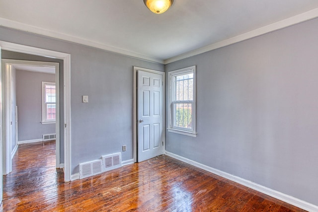 unfurnished bedroom with crown molding and dark hardwood / wood-style floors