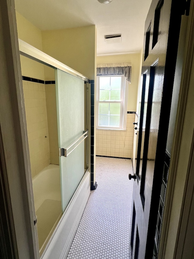 bathroom with enclosed tub / shower combo and tile walls