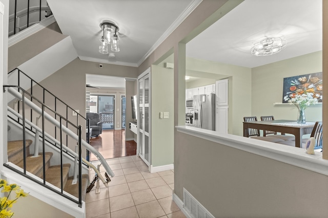 foyer with crown molding and light tile patterned flooring