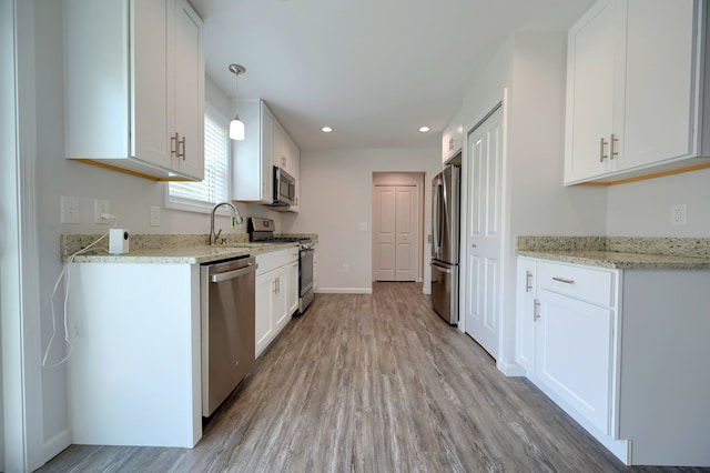 kitchen featuring light stone countertops, appliances with stainless steel finishes, white cabinets, and decorative light fixtures