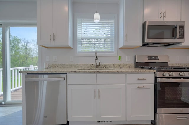 kitchen featuring light stone counters, stainless steel appliances, sink, and white cabinets