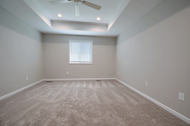 unfurnished room featuring a raised ceiling, carpet flooring, and ceiling fan