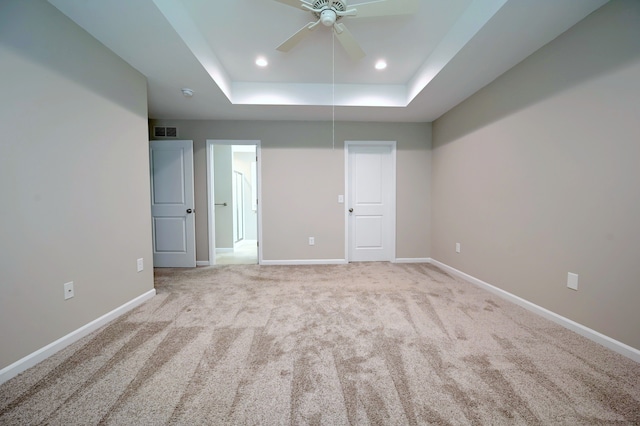 spare room with light colored carpet, ceiling fan, and a tray ceiling