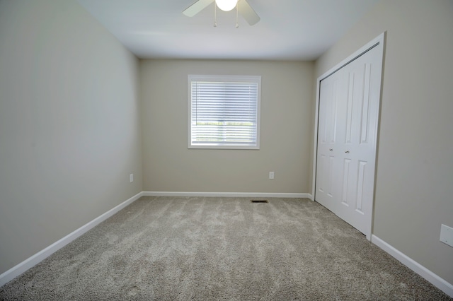 unfurnished bedroom featuring ceiling fan, a closet, and light carpet