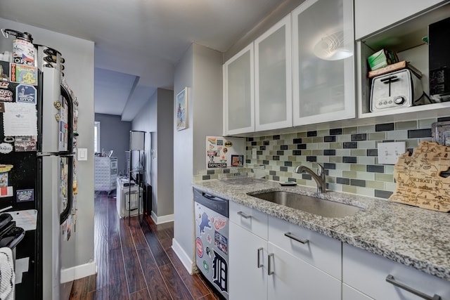 kitchen with appliances with stainless steel finishes, white cabinetry, backsplash, light stone countertops, and dark hardwood / wood-style flooring