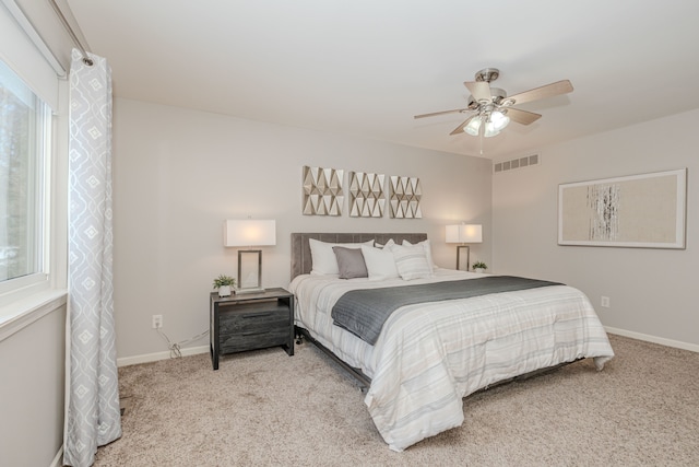 bedroom featuring light carpet, multiple windows, and ceiling fan