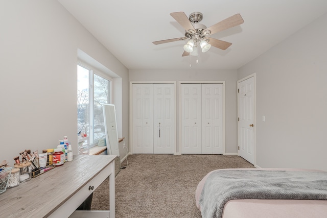 carpeted bedroom with ceiling fan and two closets