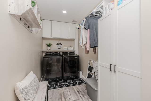 laundry room with cabinets, light wood-type flooring, and washing machine and clothes dryer