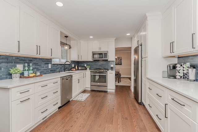 kitchen with white cabinetry, pendant lighting, stainless steel appliances, and sink