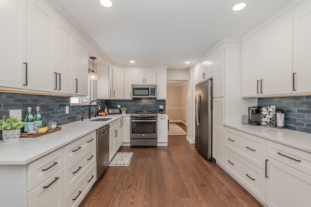 kitchen with hanging light fixtures, appliances with stainless steel finishes, sink, and white cabinets