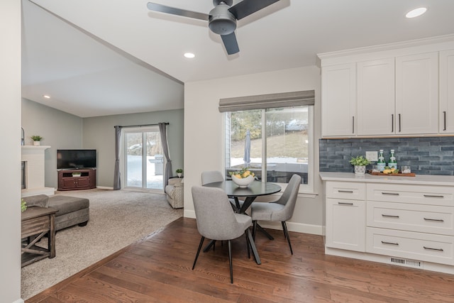 dining room featuring a fireplace, ceiling fan, and dark hardwood / wood-style floors