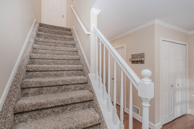 staircase with ornamental molding and hardwood / wood-style floors