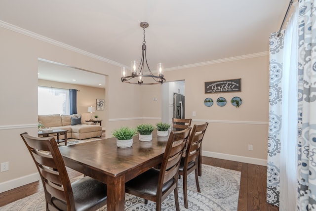 dining room featuring ornamental molding, an inviting chandelier, and dark hardwood / wood-style flooring