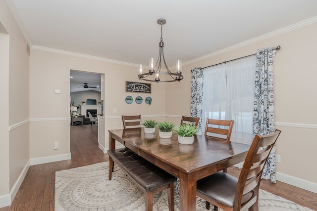 dining space with hardwood / wood-style floors, crown molding, and ceiling fan with notable chandelier