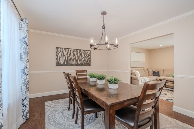 dining room with hardwood / wood-style flooring, crown molding, and an inviting chandelier