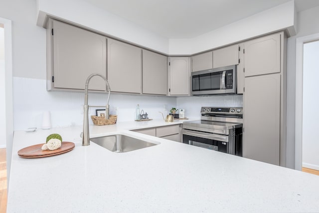 kitchen featuring stainless steel appliances, gray cabinets, and sink