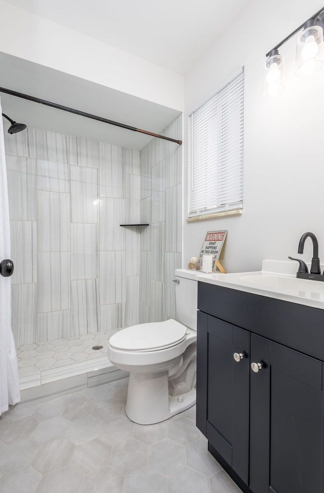 bathroom featuring tiled shower, vanity, toilet, and tile patterned flooring