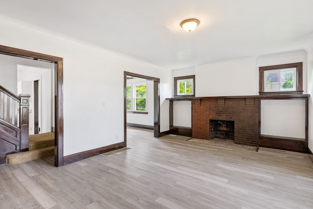 unfurnished living room with a fireplace and light hardwood / wood-style floors