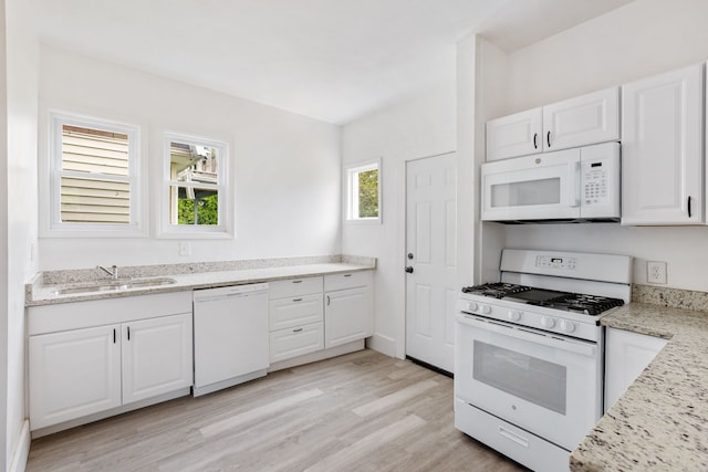 kitchen with white cabinetry, sink, light wood-type flooring, light stone countertops, and white appliances