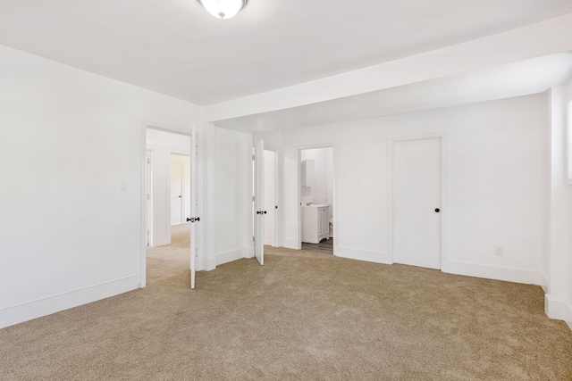 unfurnished bedroom featuring ensuite bath and light colored carpet