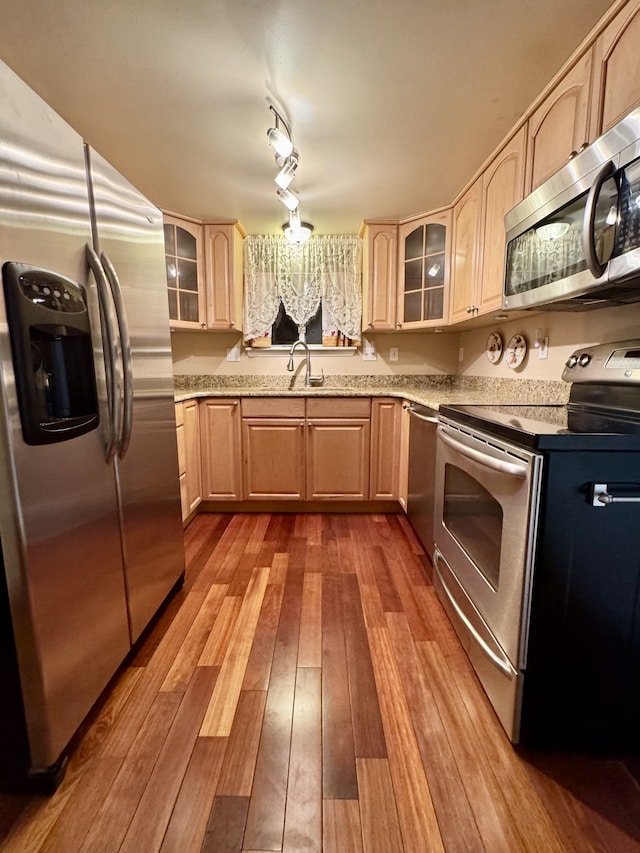 kitchen with light brown cabinetry, sink, wood-type flooring, and stainless steel appliances