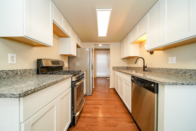 kitchen with white cabinetry, sink, stainless steel appliances, and light wood-type flooring