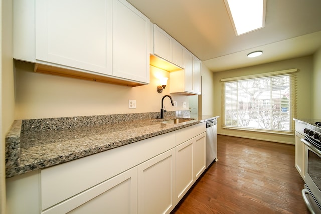 kitchen with sink, dark wood-type flooring, appliances with stainless steel finishes, white cabinetry, and light stone countertops