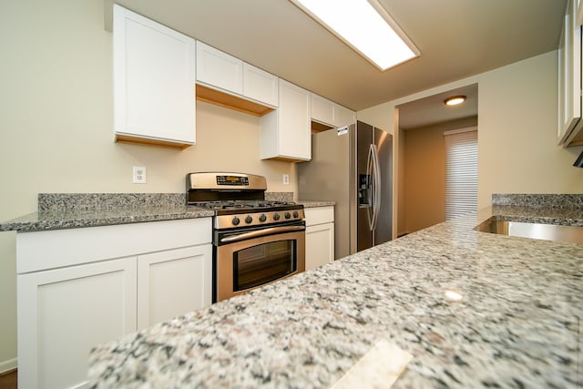 kitchen with light stone counters, stainless steel appliances, sink, and white cabinets