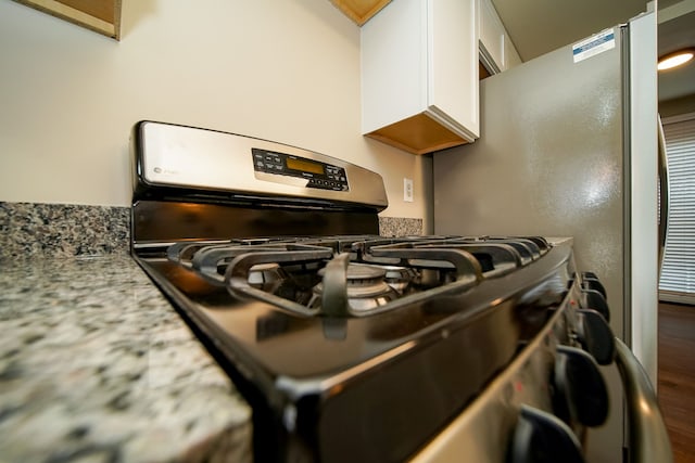 room details featuring white cabinetry, gas range, and light stone countertops