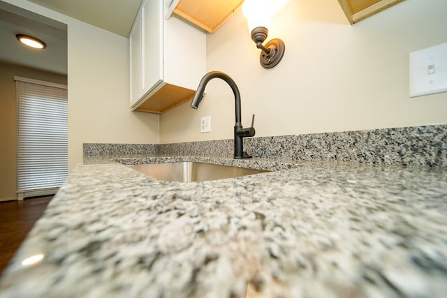 details featuring light stone counters, white cabinetry, and sink