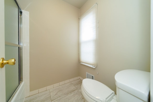 bathroom with bath / shower combo with glass door, tile patterned floors, and toilet