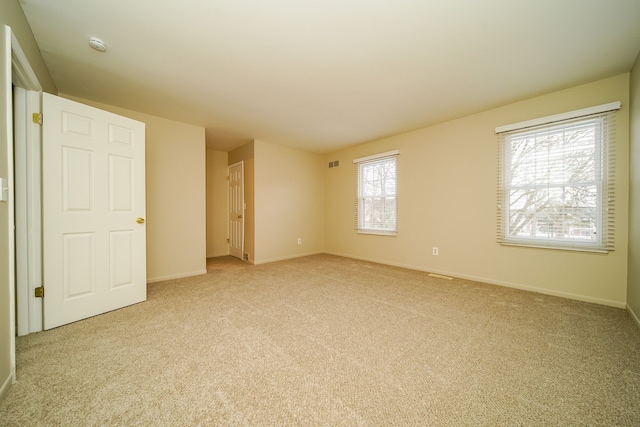 spare room featuring light carpet and a wealth of natural light