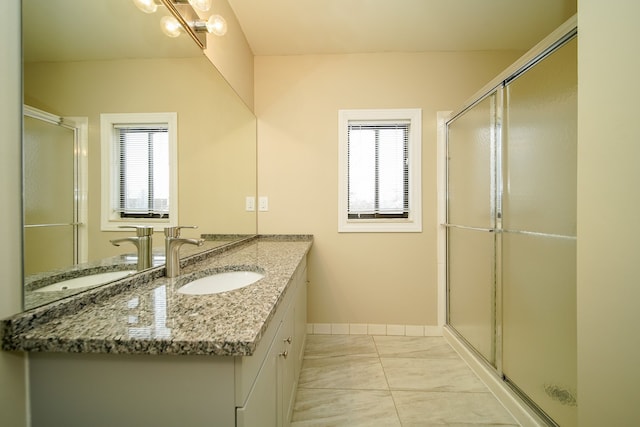 bathroom with vanity, a shower with shower door, and a healthy amount of sunlight