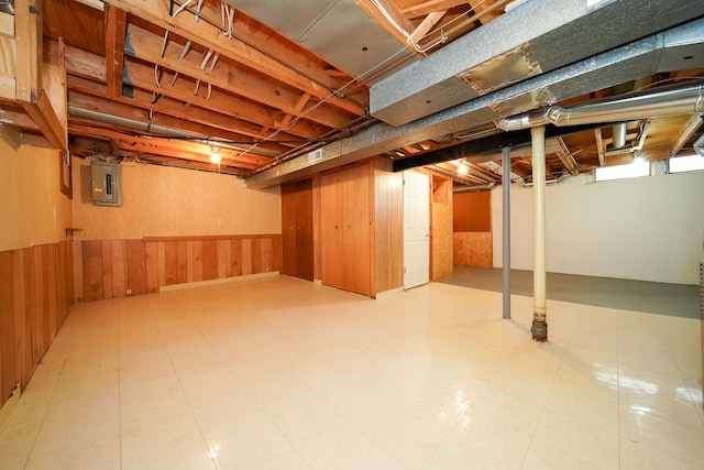 basement featuring wooden walls and electric panel