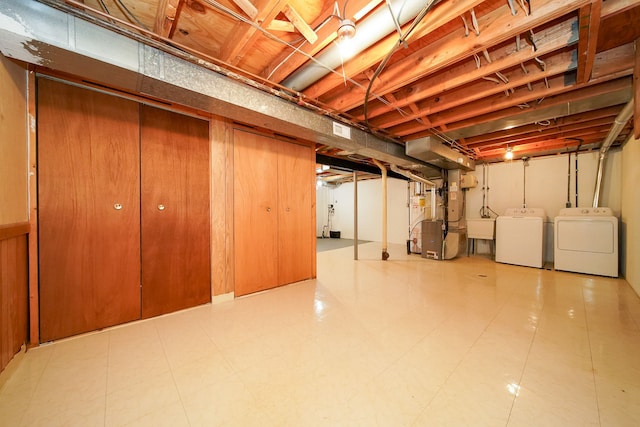 basement featuring washing machine and clothes dryer, sink, and heating unit