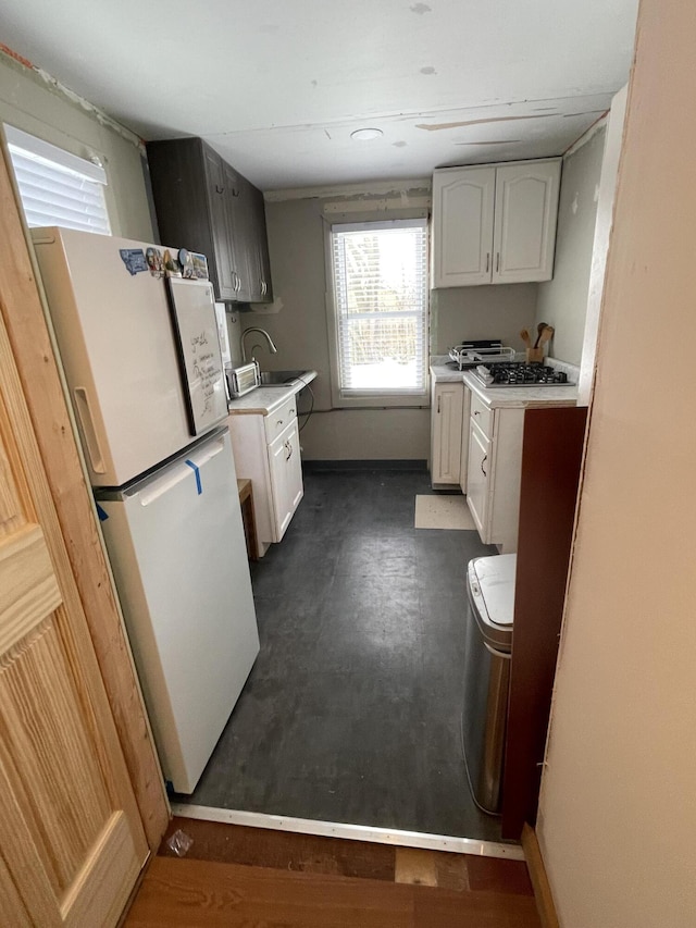 kitchen featuring white refrigerator, sink, white cabinets, and stainless steel gas stovetop