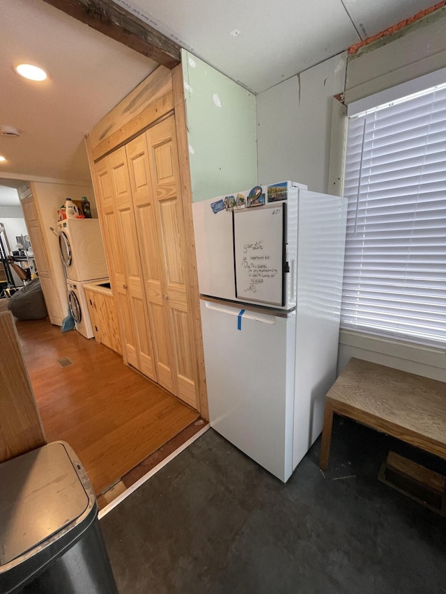 kitchen featuring dark wood-type flooring, stacked washer / drying machine, and white fridge