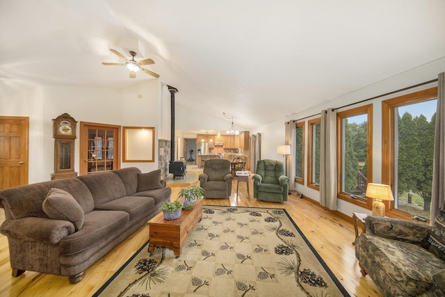 living room featuring ceiling fan with notable chandelier, vaulted ceiling, and light wood-type flooring