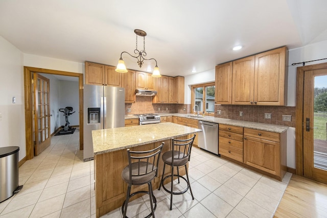 kitchen with a kitchen island, appliances with stainless steel finishes, sink, hanging light fixtures, and a healthy amount of sunlight