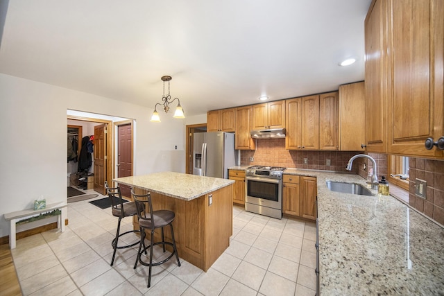 kitchen featuring sink, decorative light fixtures, a center island, stainless steel appliances, and backsplash