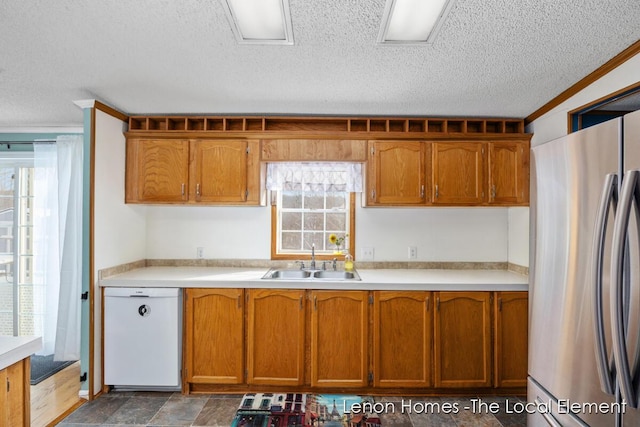 kitchen featuring white dishwasher, sink, stainless steel refrigerator, and a healthy amount of sunlight