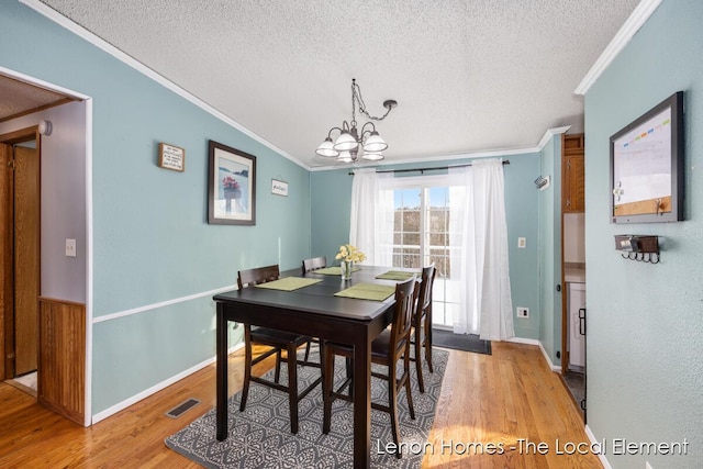 dining area with crown molding, a chandelier, light hardwood / wood-style floors, and a textured ceiling