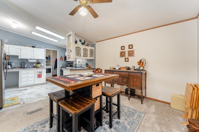 carpeted dining space featuring ceiling fan, vaulted ceiling, and a textured ceiling