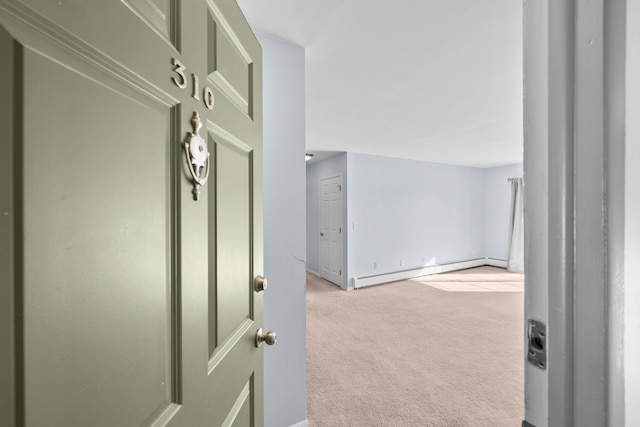 hall with light colored carpet and a baseboard heating unit