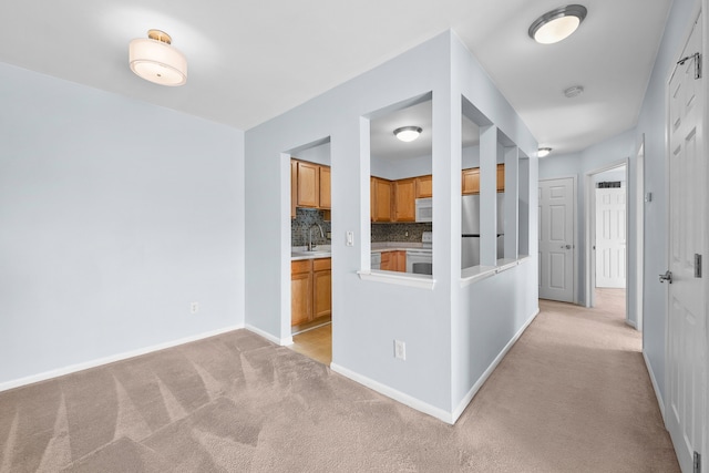 corridor with sink and light colored carpet