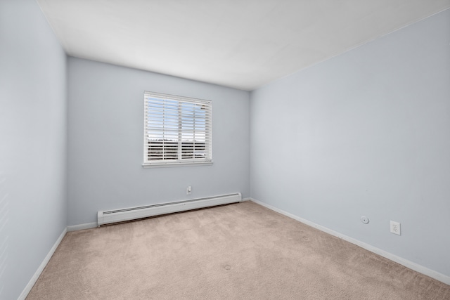 spare room featuring light carpet and a baseboard heating unit