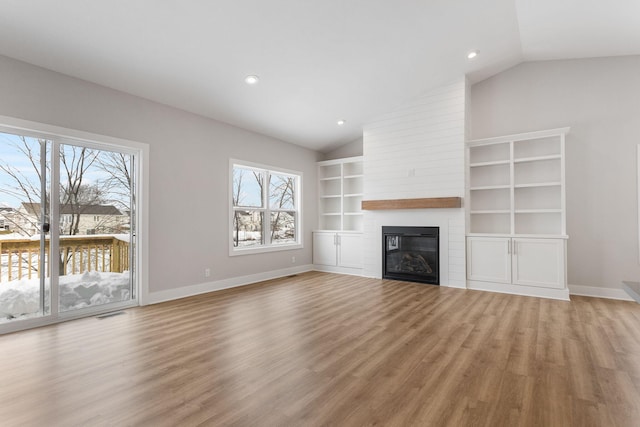 unfurnished living room with lofted ceiling, wood-type flooring, and a large fireplace