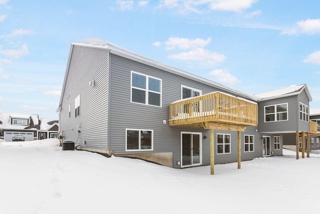 snow covered rear of property with central AC and a deck